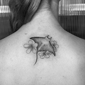 Tatouage d'une raie manta en réalisme avec des fleurs de tiaré tahiti